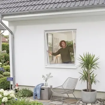Frau setzt einen Fliegengitter Spannrahmen in ein geöffnetes Fenster ein