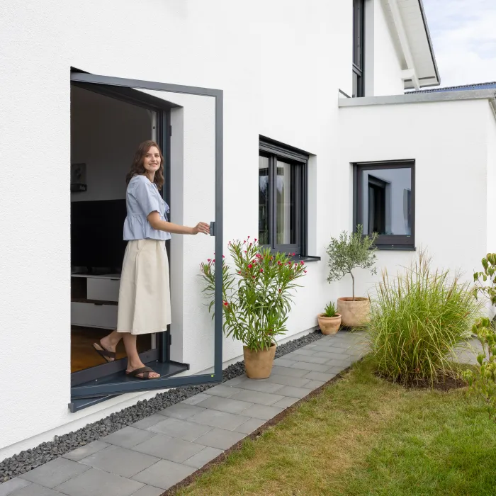 Abendliche Terrassenszene mit geöffneter Fliegengitter Schiebetür und vier Personen