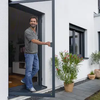Mann ffnet eine magefertigte Fliegengitter Tr an einer modernen Terrasse