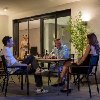 Abendliche Terrassenszene mit geffneter Fliegengitter Schiebetr und vier Personen